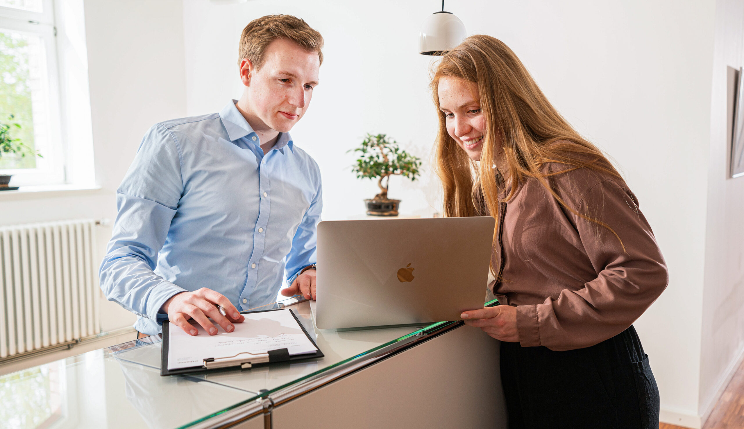 Zwei Menschen stehen an einem Hochtisch und schauen in einen Laptop, stellen eine Online-Anfrage zu den Leistungen von thamm, einer Unternehmensberatung in Osnabrück.