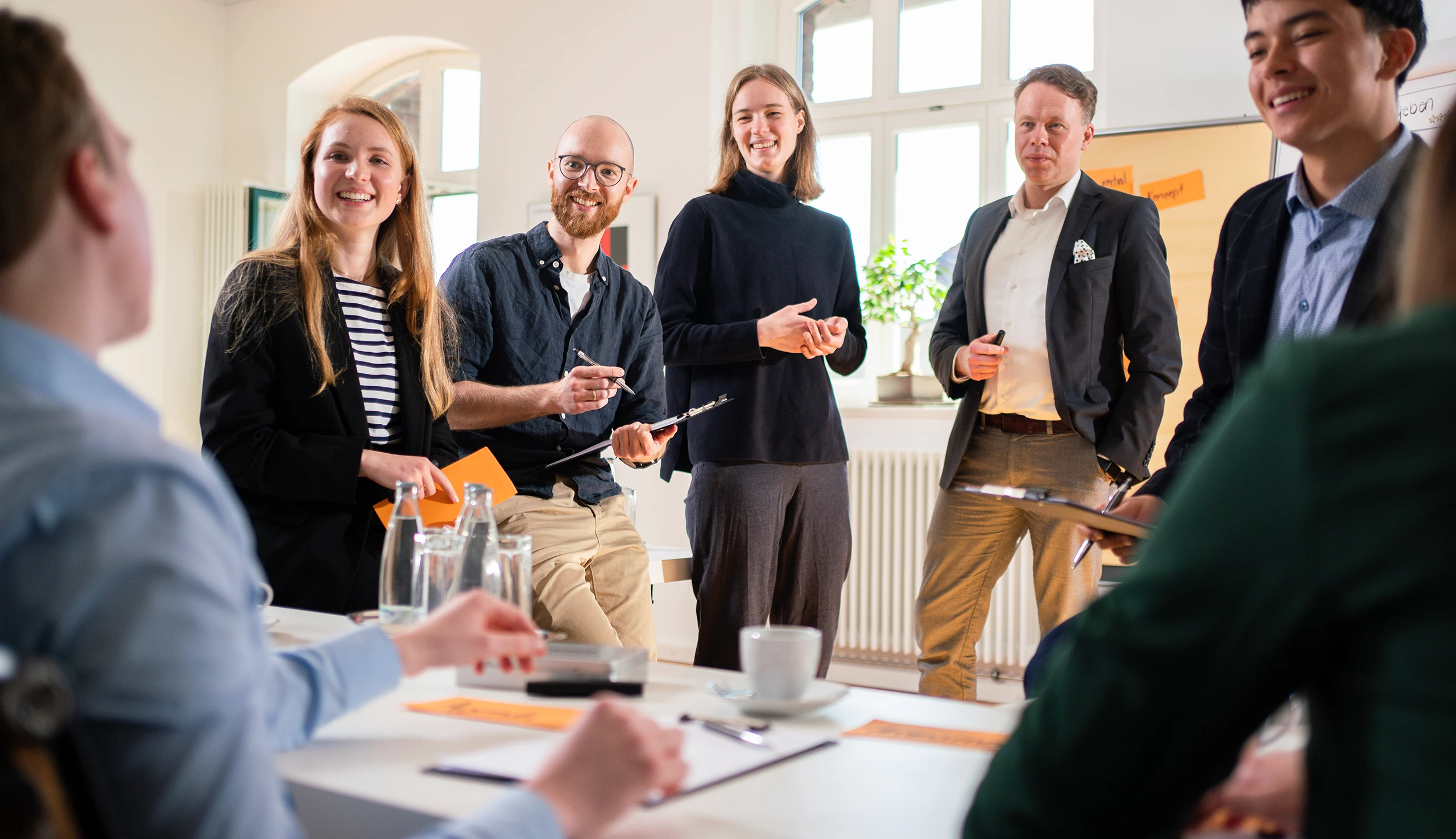 Ein Seminar oder Workshop bei //thamm in Osnabrück, mit sieben lächelnden Menschen, die sich gerade in einer Diskussion befinden.